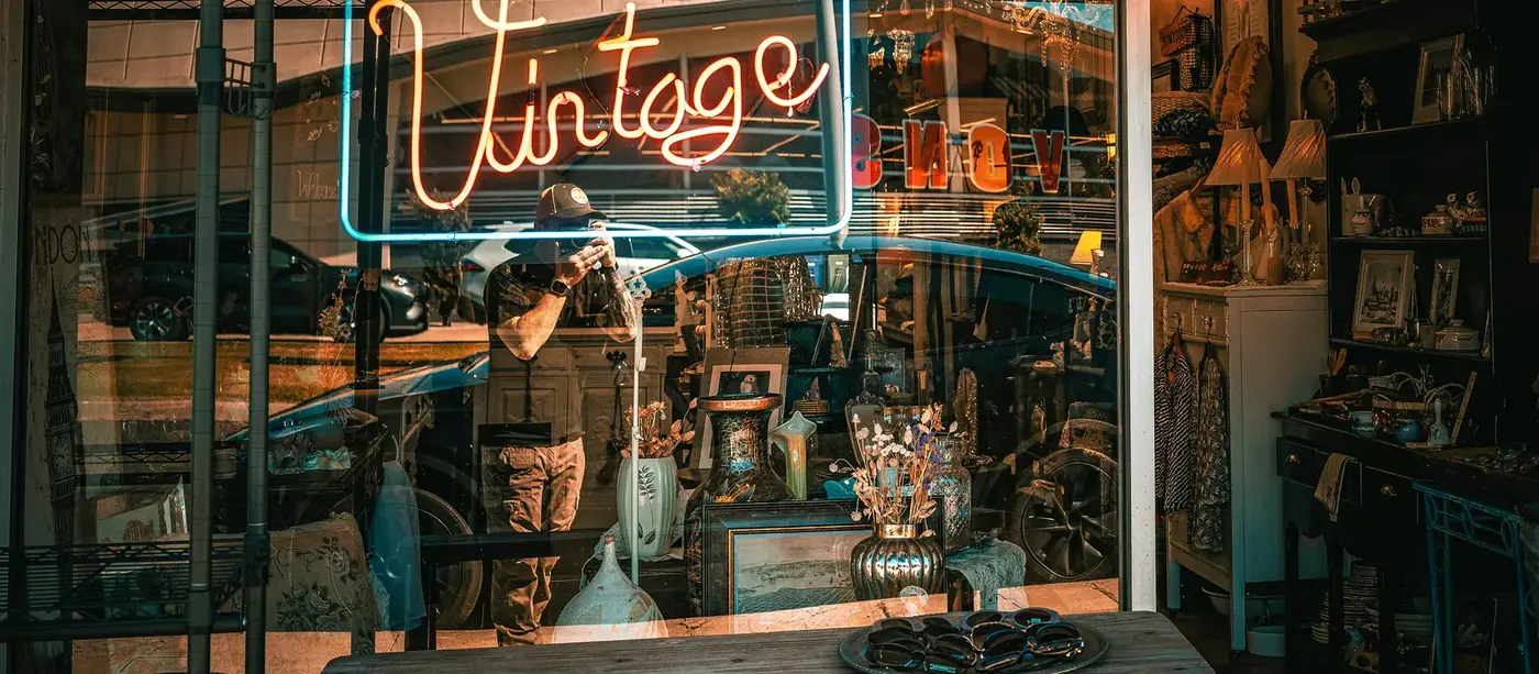 Vintage shop window display with furniture, chandelier, decor, and glowing sign